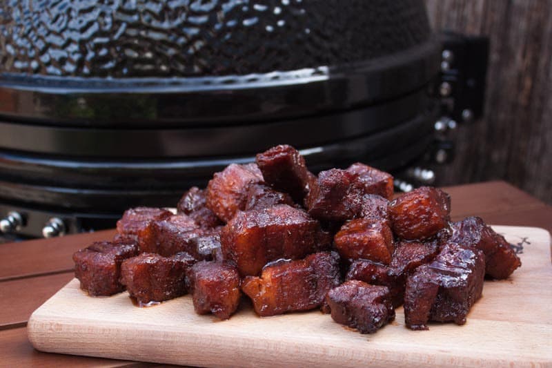 Sticky pork belly op een houten plank bij de kamado