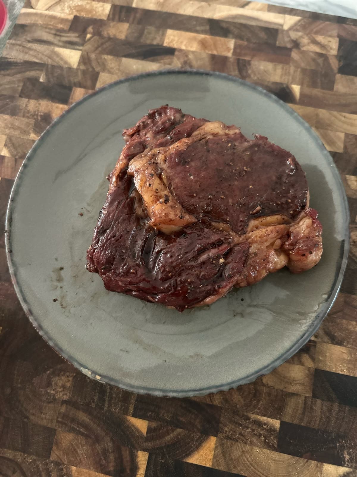 Gegrilde ribeye van de kamado op een grijs bord